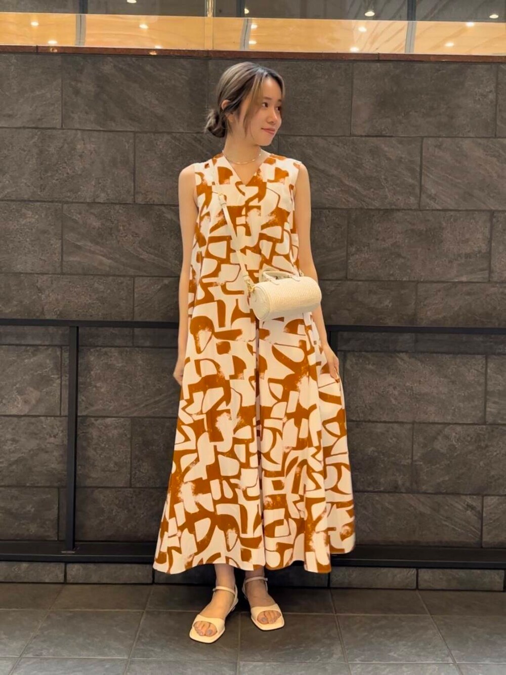 ホワイト系のサンダル、オレンジ系のワンピースを着用したレディースの春コーディネートの2枚目の写真