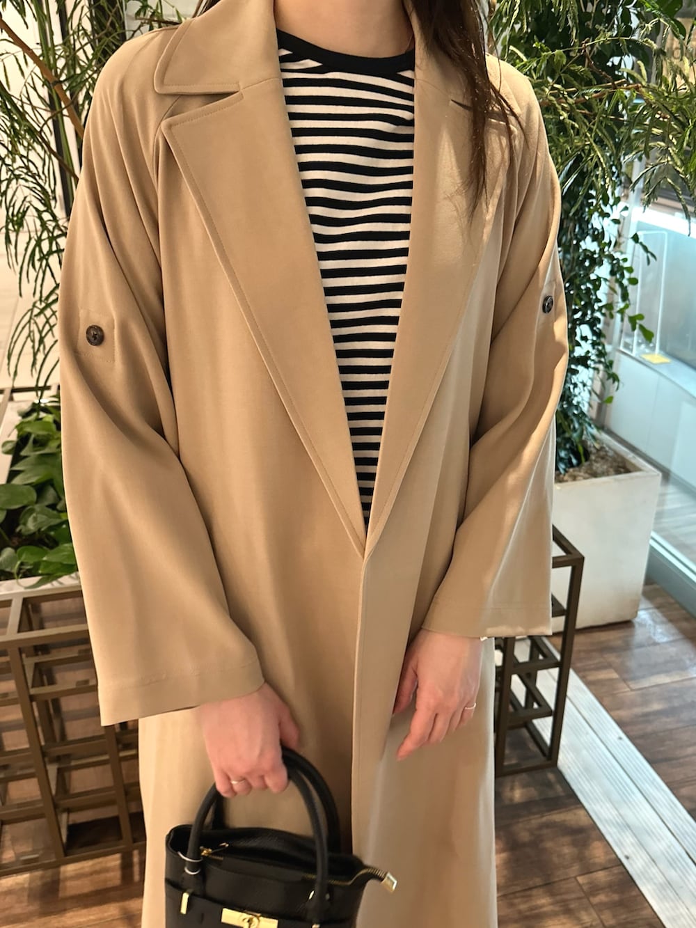 ベージュ系のトレンチコート、ホワイト系のTシャツ/カットソー、ブラック系のショルダーバッグを着用したレディースの春コーディネートの5枚目の写真