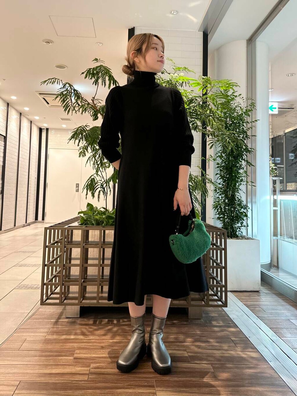 シルバー系のブーツ、ブラック系のワンピース、グリーン系のショルダーバッグを着用したレディースの秋コーディネートの3枚目の写真