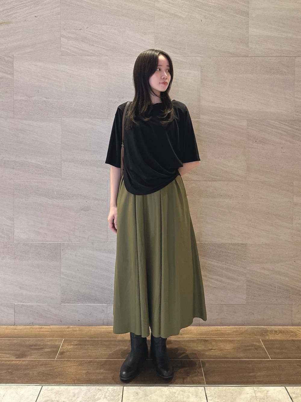 ブラック系のTシャツ/カットソー、グリーン系のスカート、ブラック系のブーツを着用したレディースの秋コーディネートの2枚目の写真