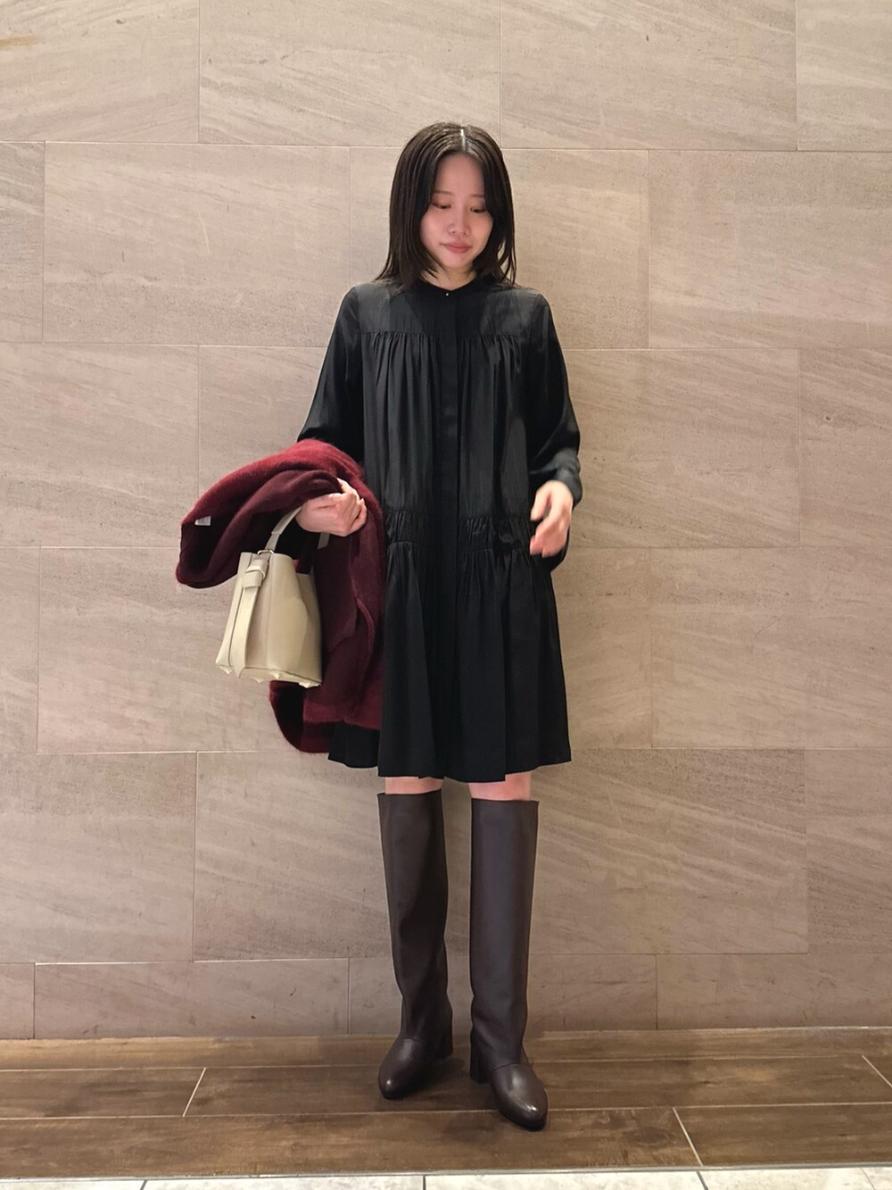ブラック系のワンピース、レッド系のカーディガン/ボレロ、ベージュ系のハンドバッグを着用したレディースの秋コーディネートの3枚目の写真