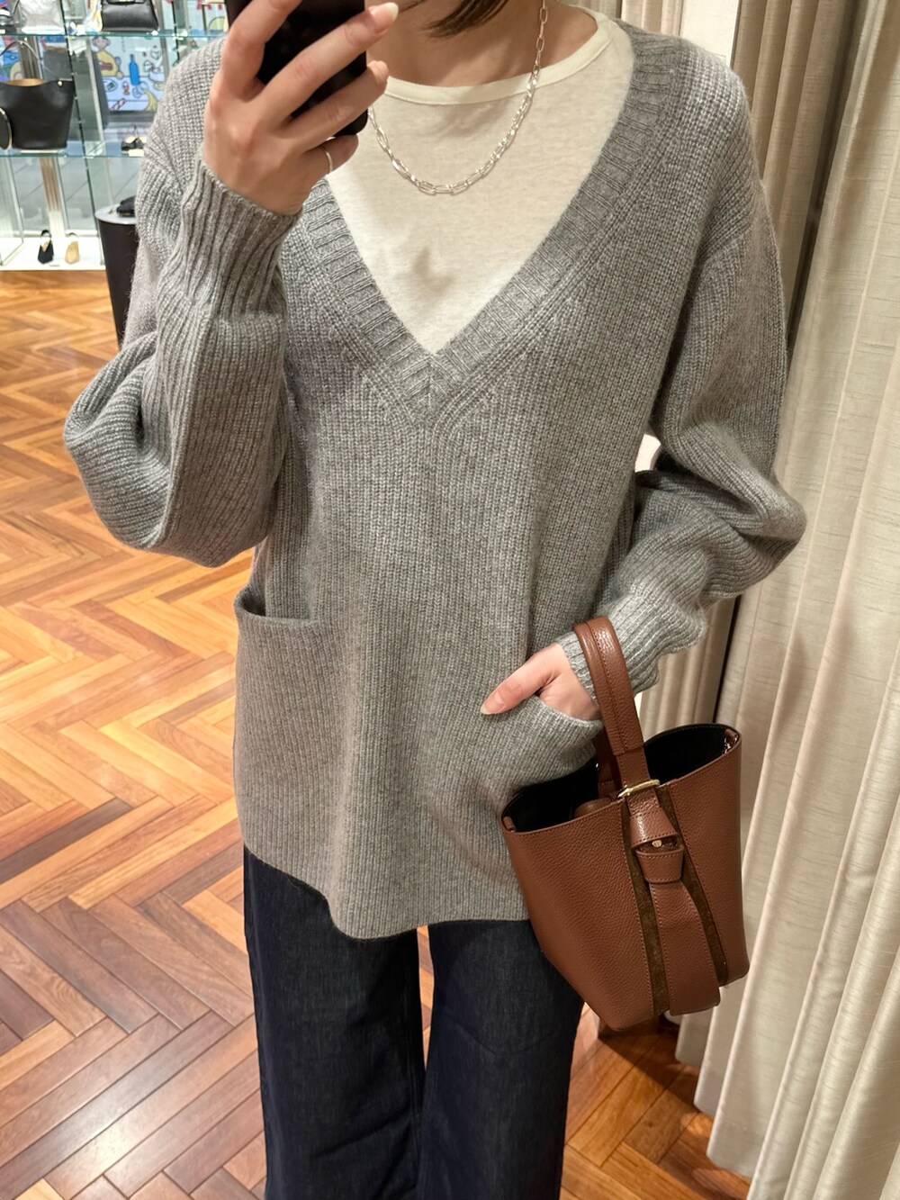 グレー系のニット/セーター、ホワイト系のTシャツ/カットソー、ブルー系のデニムパンツを着用したレディースの秋コーディネートの3枚目の写真