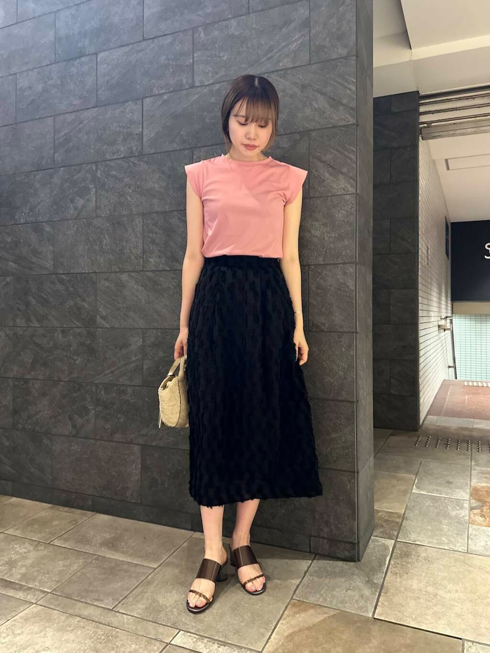ベージュ系のかごバッグ、ピンク系のTシャツ/カットソー、ブラック系のスカートを着用したレディースの夏コーディネートの5枚目の写真