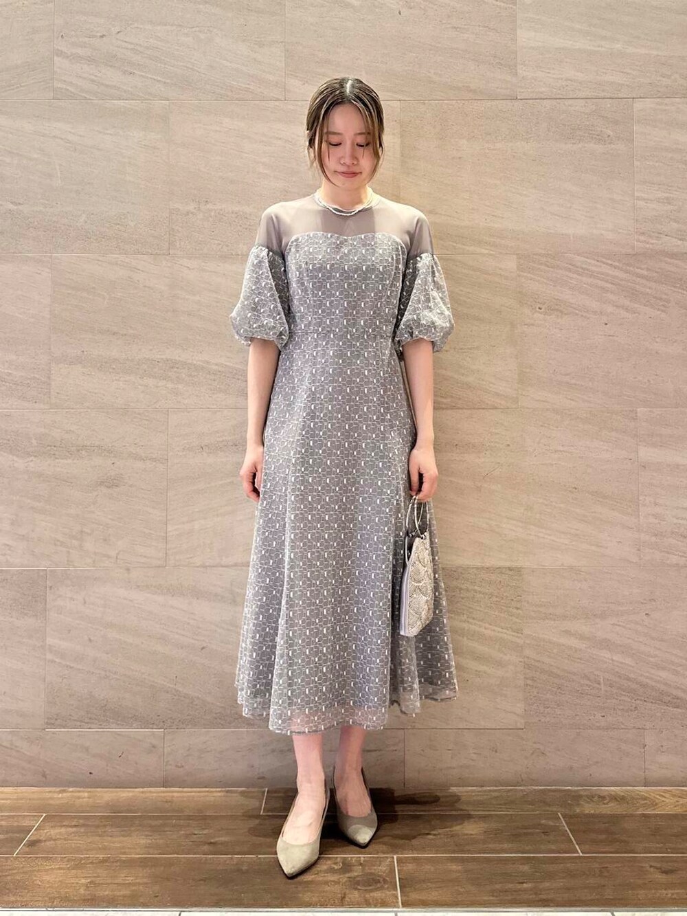 ブラウン系のパンプス、シルバー系のハンドバッグ、グレー系のワンピースを着用したレディースの春コーディネートの3枚目の写真