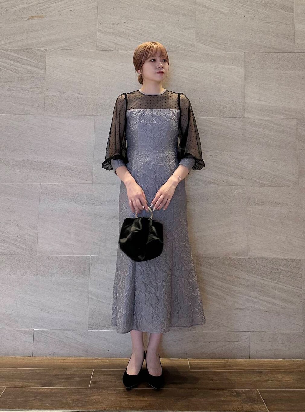 ブラック系のパンプス、ブラック系のハンドバッグ、グレー系のワンピースを着用したレディースの夏コーディネートの2枚目の写真