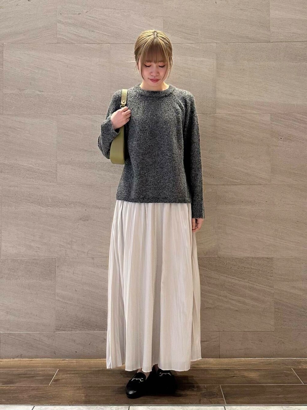 グリーン系のショルダーバッグ、ホワイト系のスカート、グレー系のニット/セーターを着用したレディースの冬コーディネートの4枚目の写真