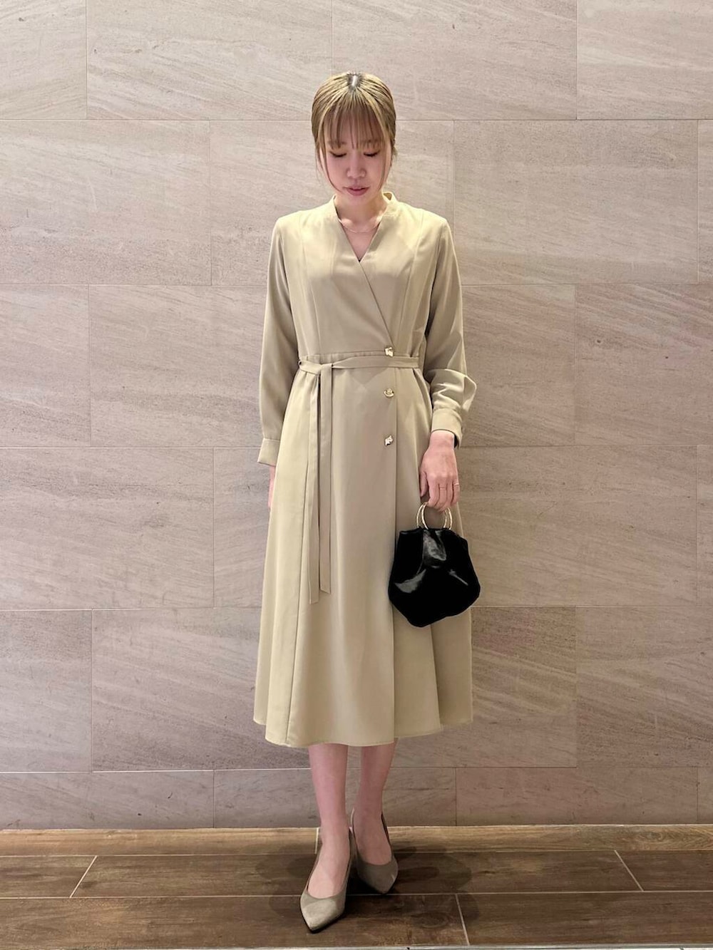 ブラウン系のパンプス、ブラック系のハンドバッグ、ベージュ系のワンピースを着用したレディースの冬コーディネートの4枚目の写真