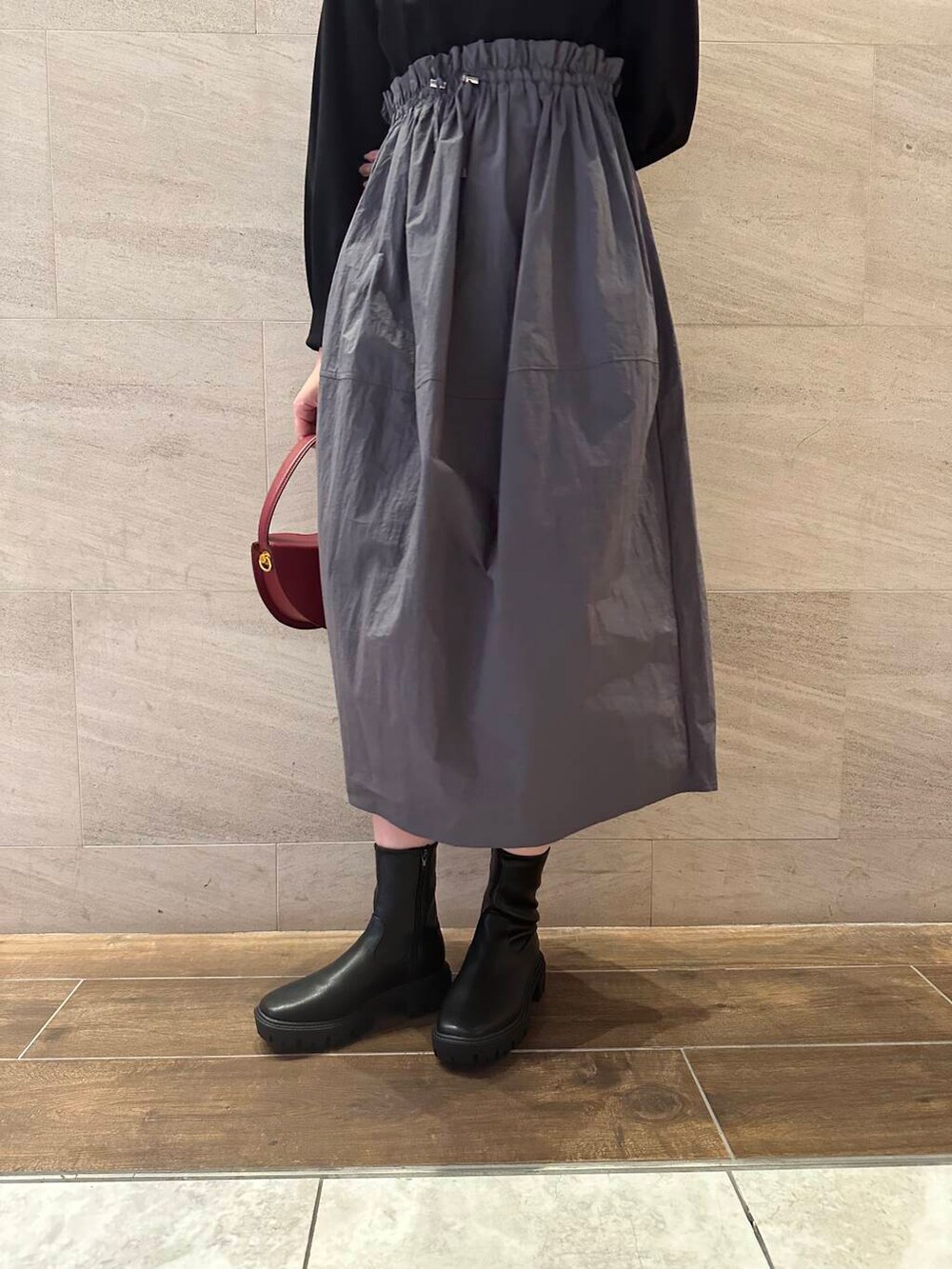 ブラック系のブーツ、ブラック系のワンピース、レッド系のハンドバッグを着用したレディースの冬コーディネートの7枚目の写真