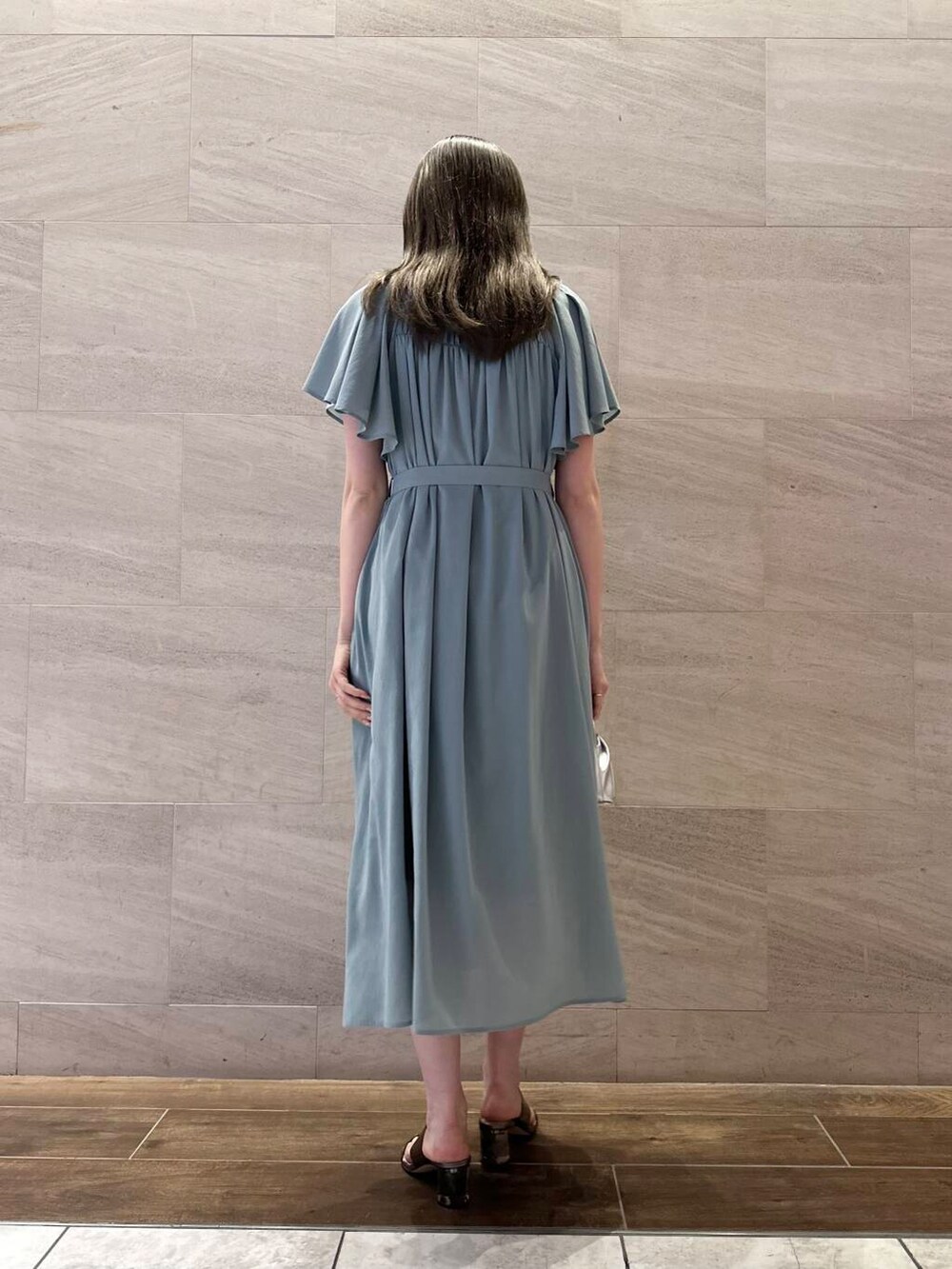 シルバー系のハンドバッグ、ブルー系のワンピース、シルバー系のリングを着用したレディースの夏コーディネートの2枚目の写真