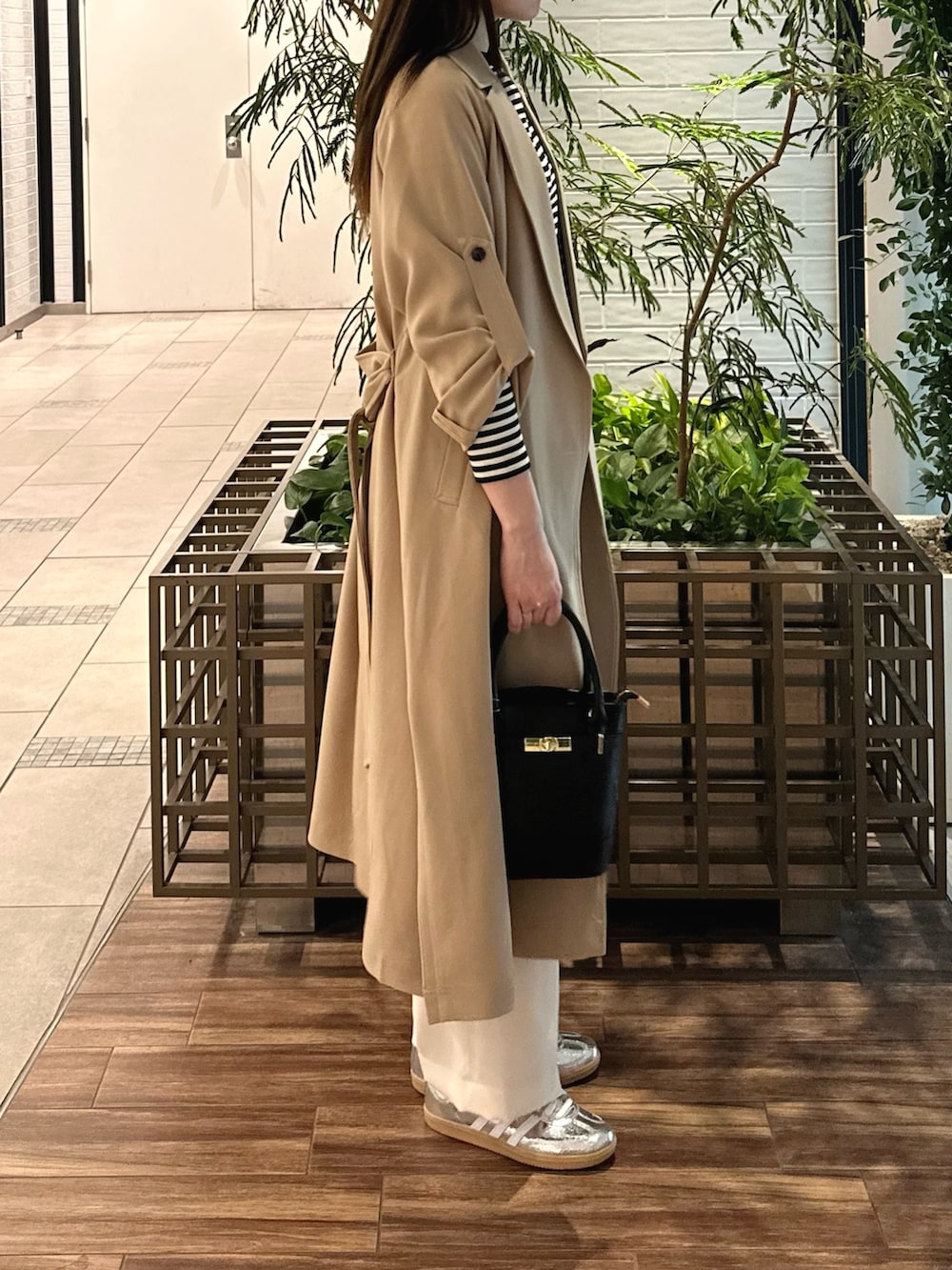 ベージュ系のトレンチコート、ホワイト系のTシャツ/カットソー、ブラック系のショルダーバッグを着用したレディースの春コーディネートの2枚目の写真