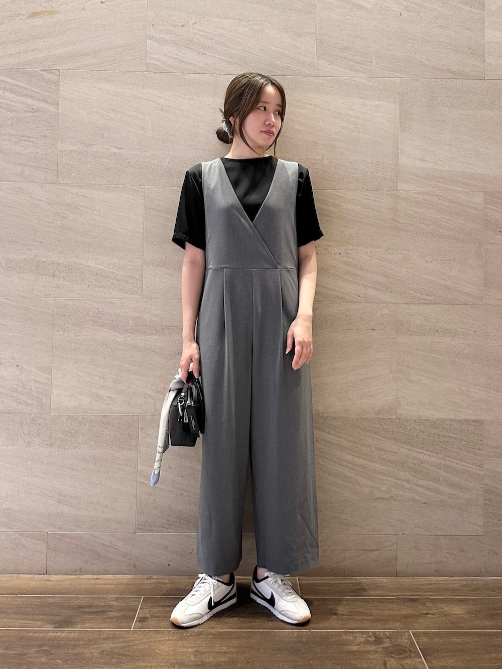 ブラック系のTシャツ/カットソー、グレー系のサロペット/オーバーオール、ホワイト系のスニーカーを着用したレディースの秋コーディネートの2枚目の写真