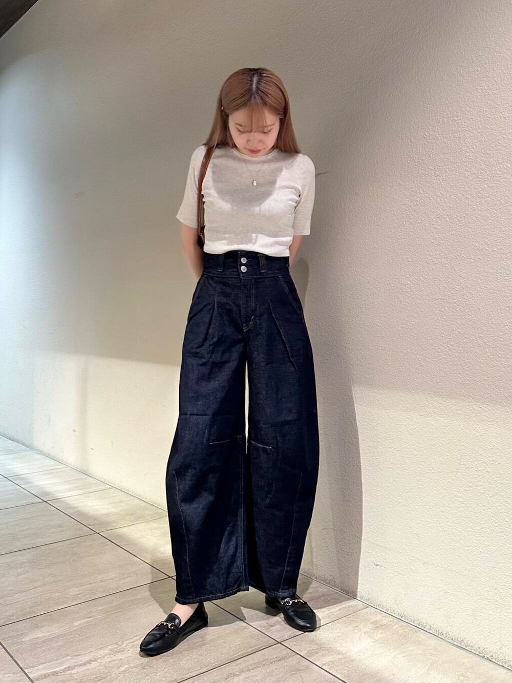 ブラック系のローファー、ホワイト系のニット/セーター、ブルー系のデニムパンツを着用したレディースの秋コーディネートの6枚目の写真