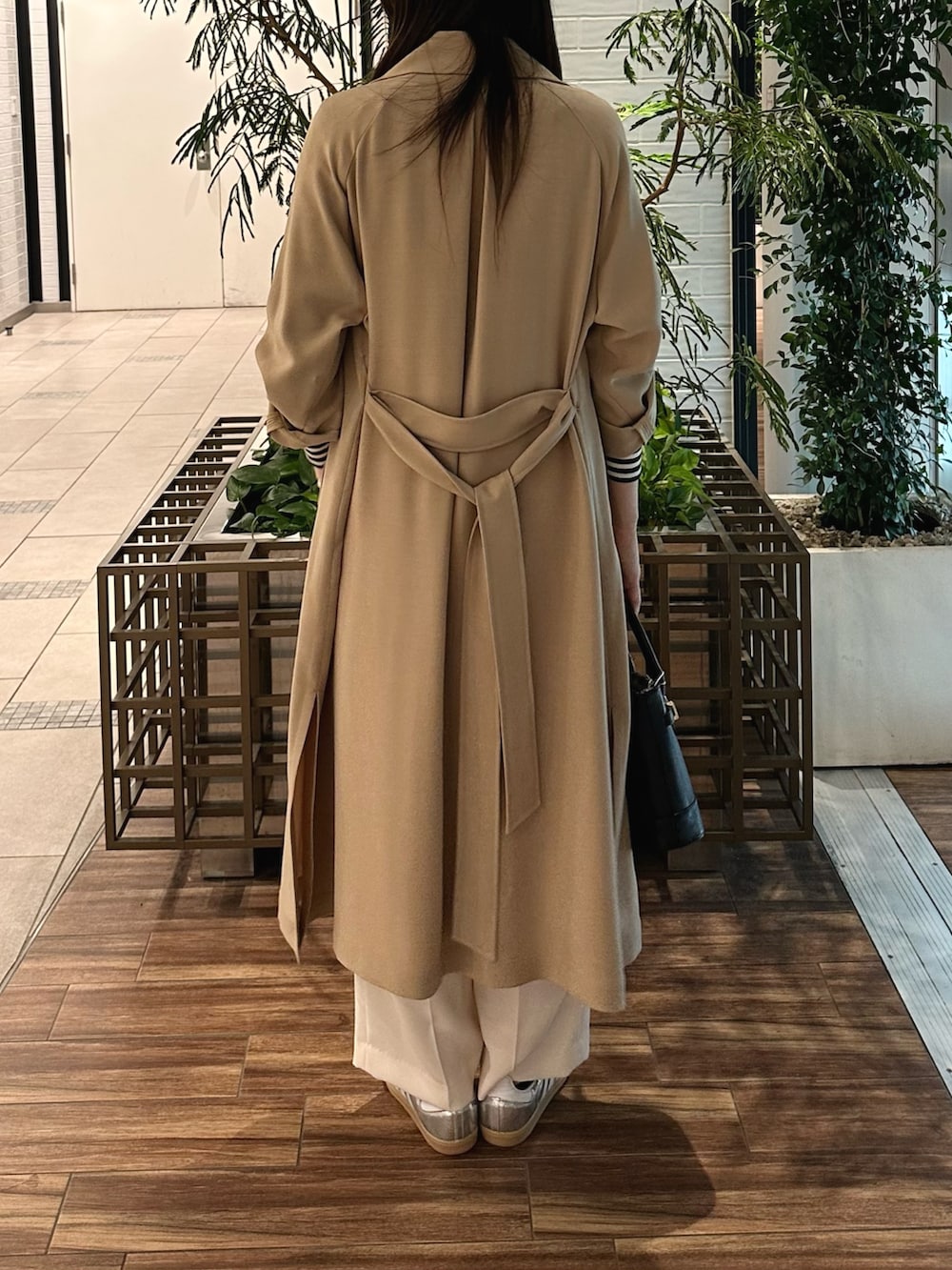 ベージュ系のトレンチコート、ホワイト系のTシャツ/カットソー、ブラック系のショルダーバッグを着用したレディースの春コーディネートの4枚目の写真