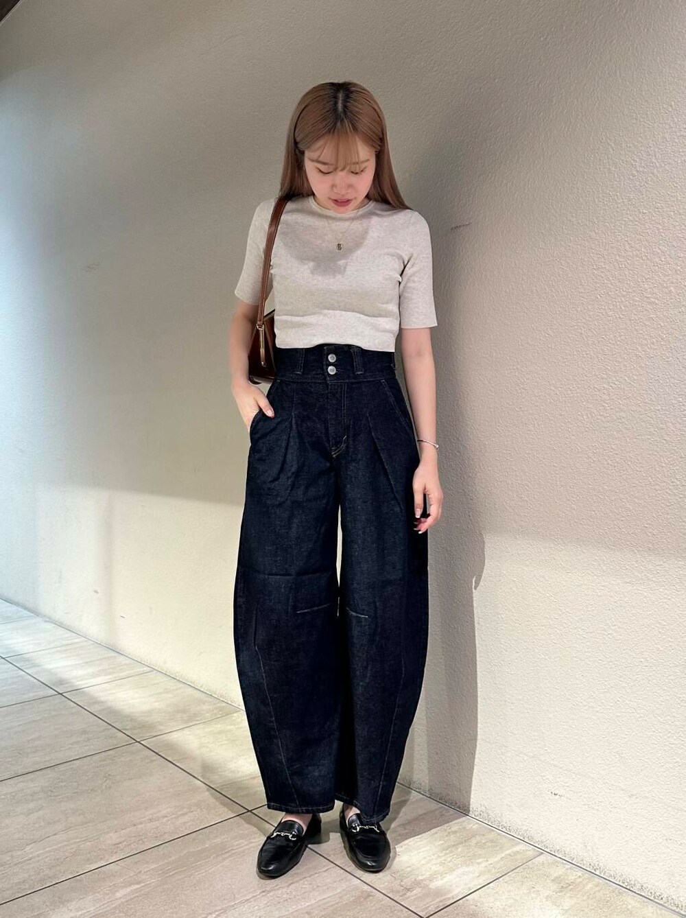 ブラック系のローファー、ホワイト系のニット/セーター、ブルー系のデニムパンツを着用したレディースの秋コーディネートの2枚目の写真