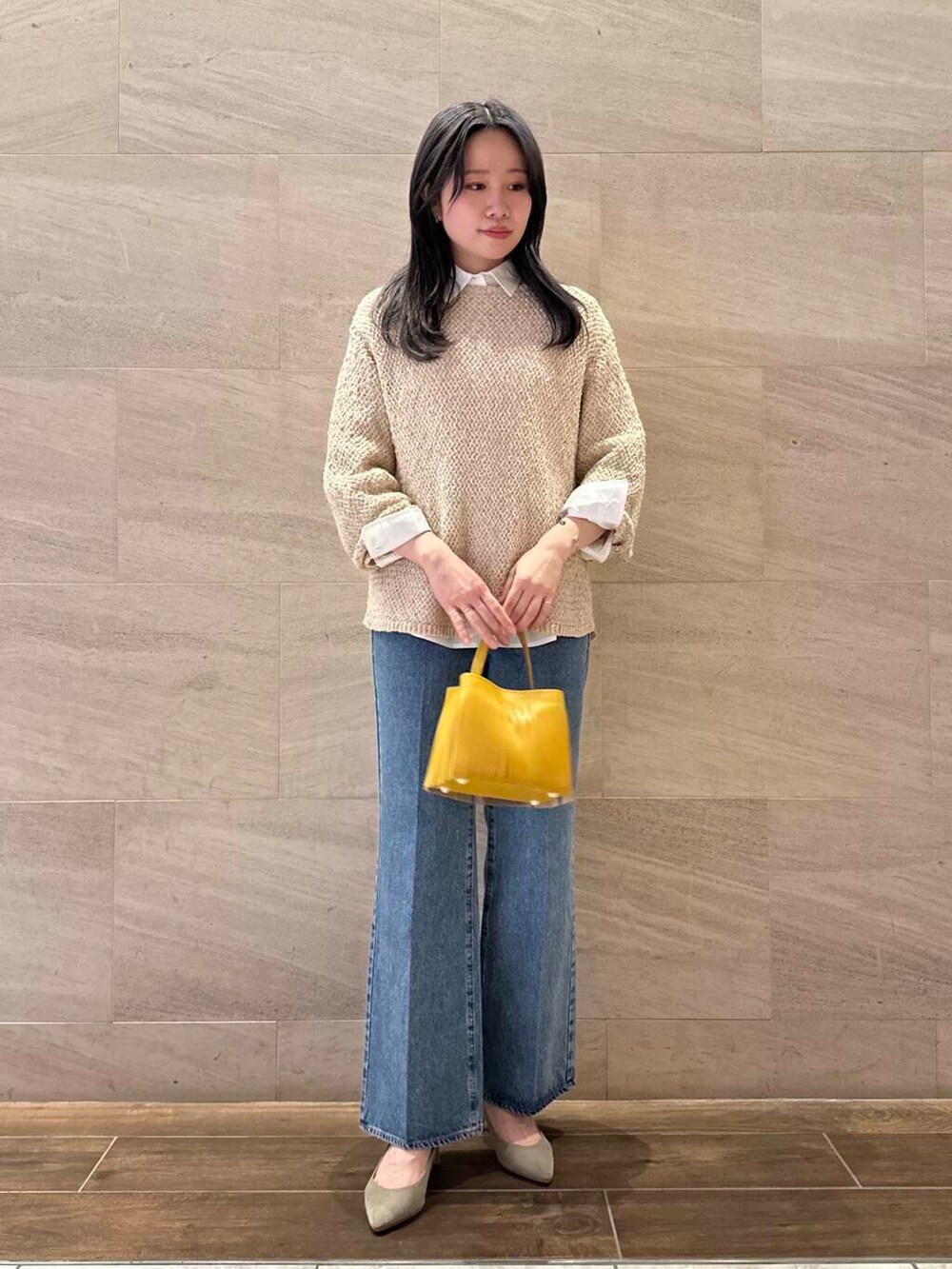 ベージュ系のニット/セーター、イエロー系のハンドバッグ、ホワイト系のシャツ/ブラウスを着用したレディースの春コーディネートの2枚目の写真