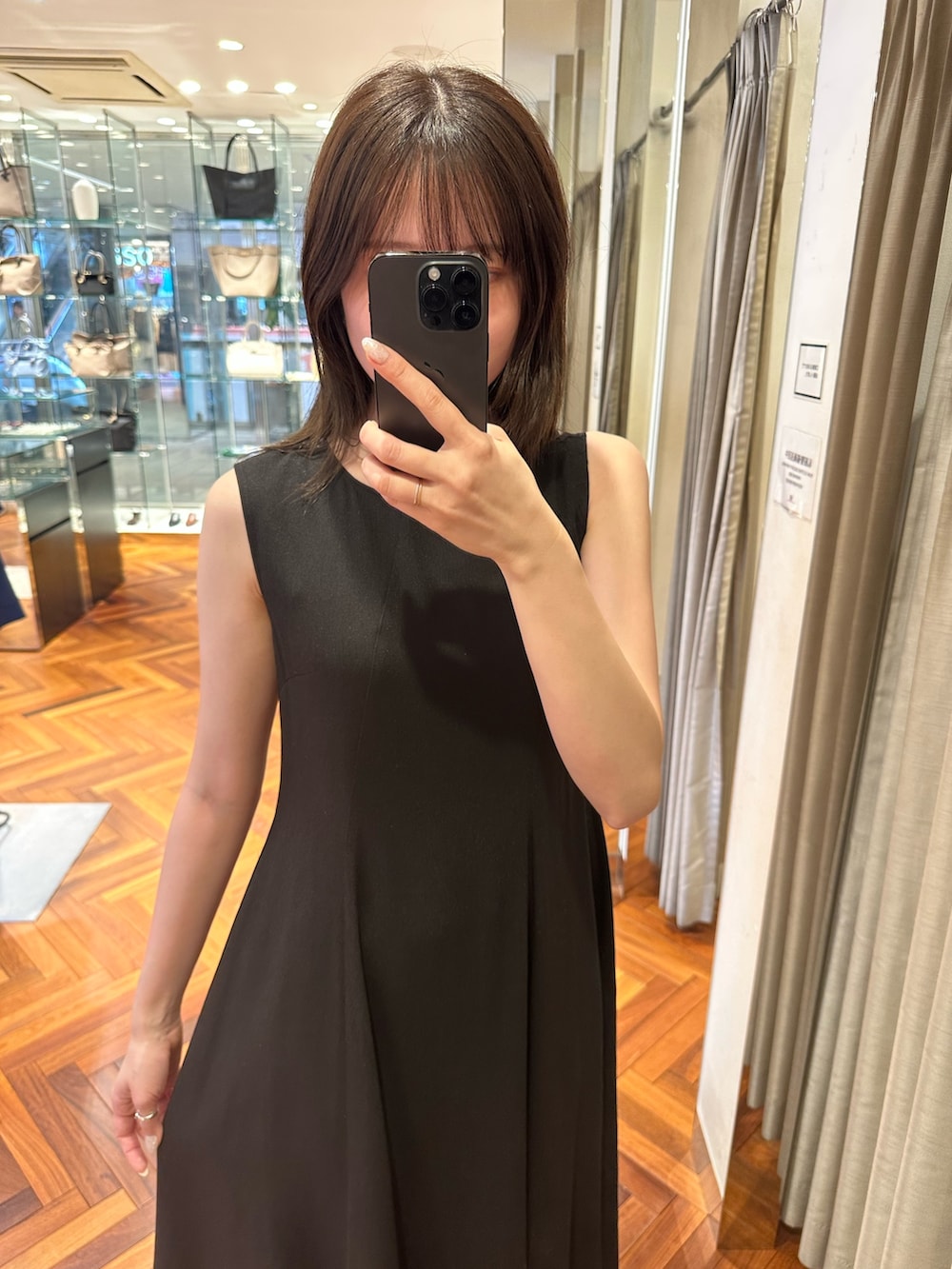 ブラック系のワンピース、ベージュ系のショルダーバッグ、ブラック系のサンダルを着用したレディースの夏コーディネートの5枚目の写真