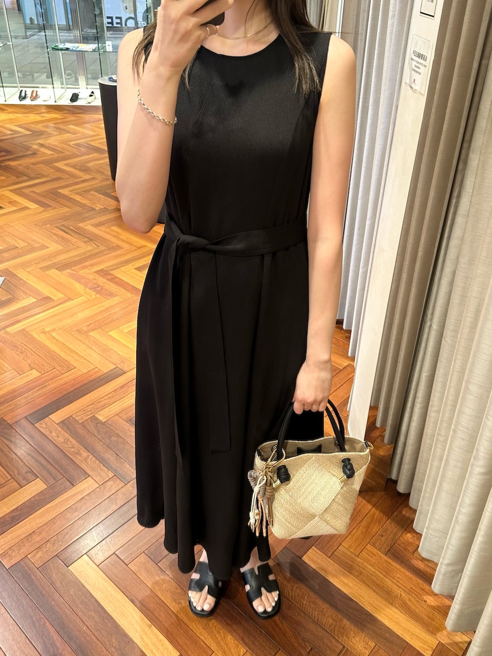 ブラック系のワンピース、ベージュ系のショルダーバッグ、ブラック系のサンダルを着用したレディースの夏コーディネートの2枚目の写真