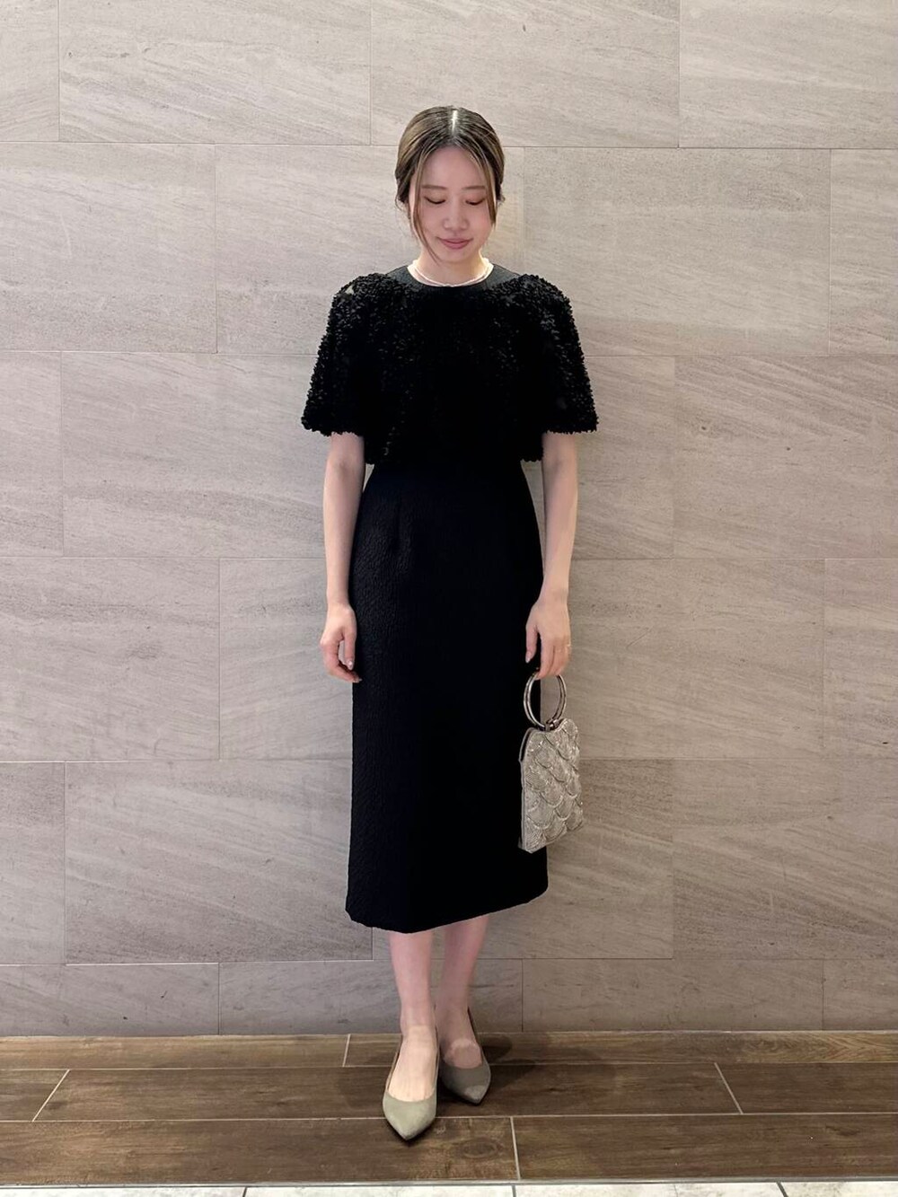 ベージュ系のハンドバッグ、ホワイト系のネックレスを着用したレディースの春コーディネートの2枚目の写真