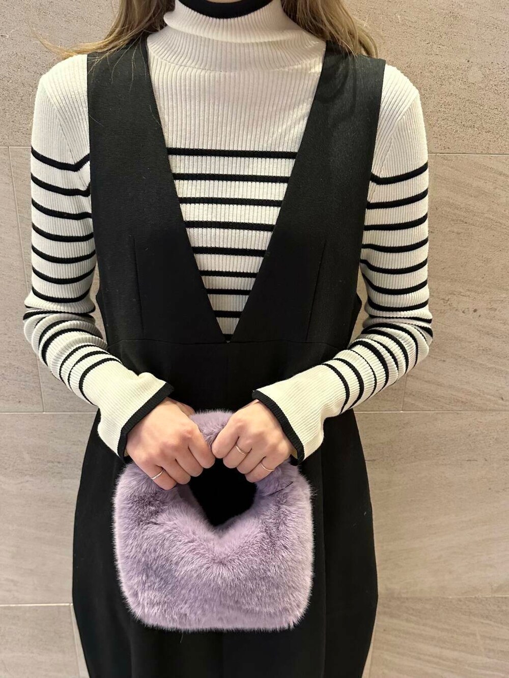 ホワイト系のニット/セーター、ブラック系のジャンパースカート、ブラック系のブーツを着用したレディースの冬コーディネートの6枚目の写真