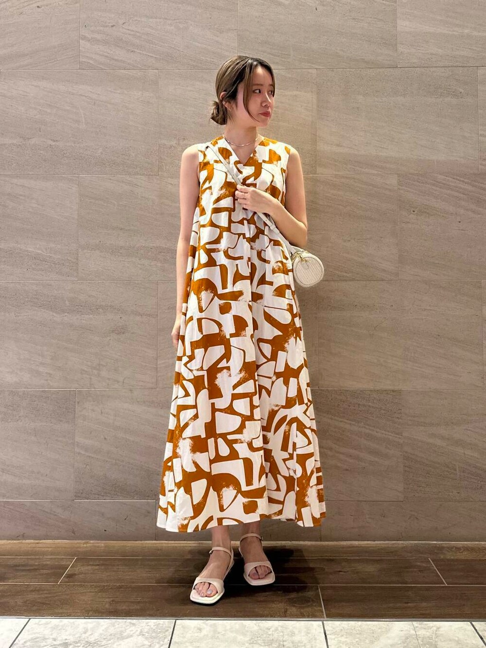 ホワイト系のサンダル、オレンジ系のワンピースを着用したレディースの春コーディネートの3枚目の写真