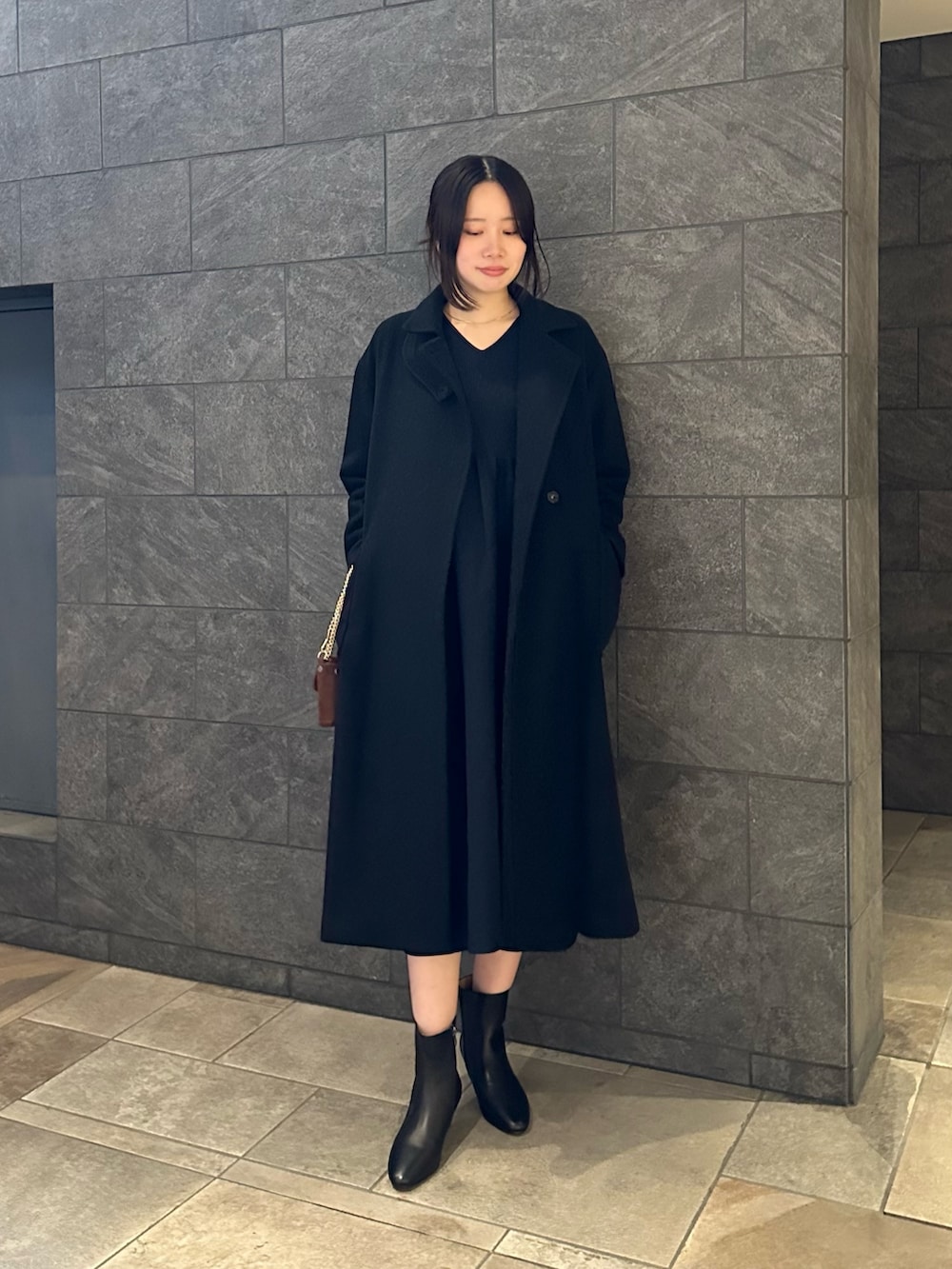 ブルー系のワンピース、ブラック系のその他アウター、ブラウン系のショルダーバッグを着用したレディースの秋コーディネートの2枚目の写真