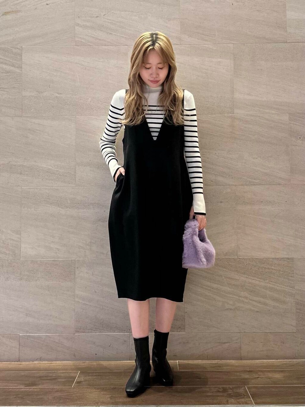 ホワイト系のニット/セーター、ブラック系のジャンパースカート、ブラック系のブーツを着用したレディースの冬コーディネートの3枚目の写真