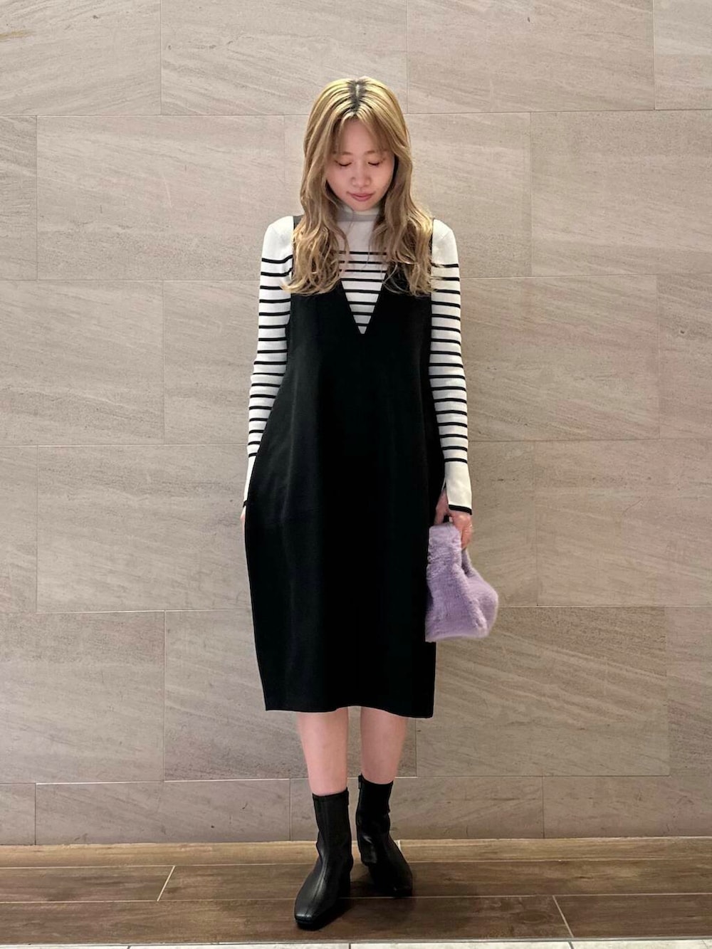 ホワイト系のニット/セーター、ブラック系のジャンパースカート、ブラック系のブーツを着用したレディースの冬コーディネートの2枚目の写真