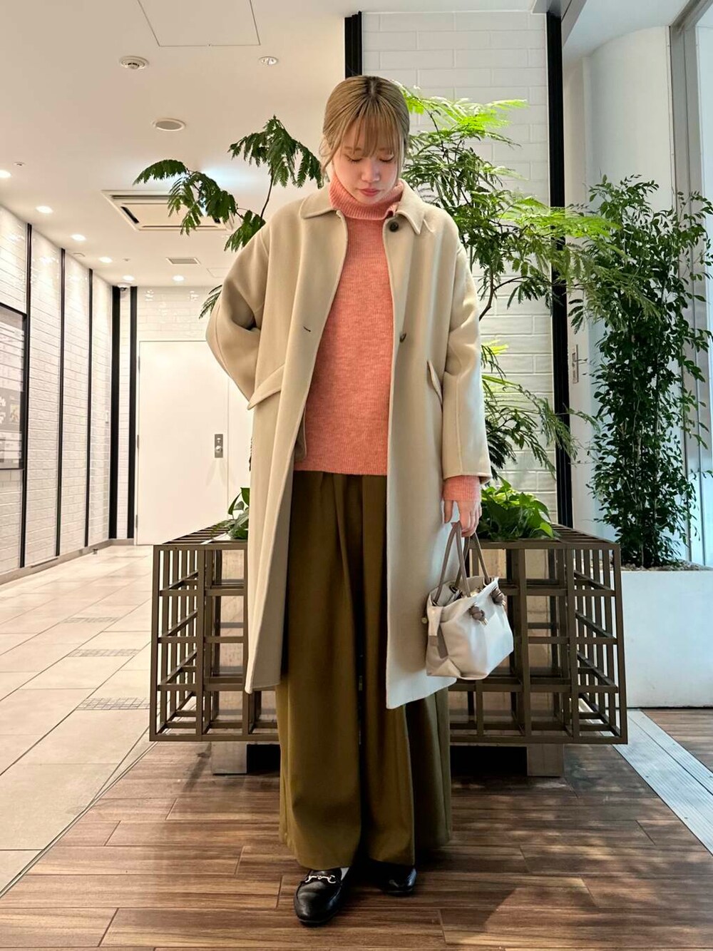 ベージュ系のステンカラーコート、ベージュ系のその他パンツ、ピンク系のニット/セーターを着用したレディースの冬コーディネートの2枚目の写真