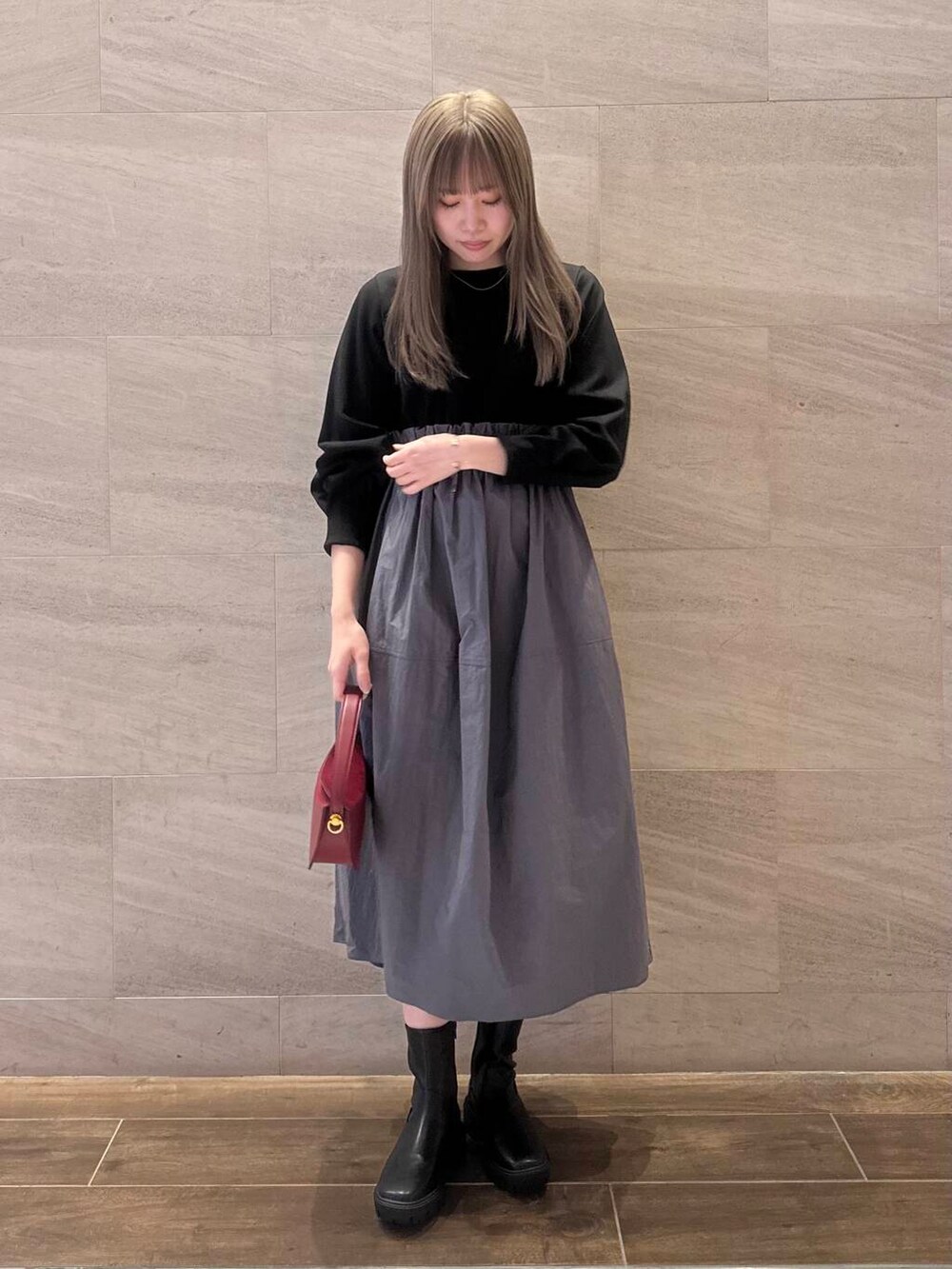 ブラック系のブーツ、ブラック系のワンピース、レッド系のハンドバッグを着用したレディースの冬コーディネートの2枚目の写真