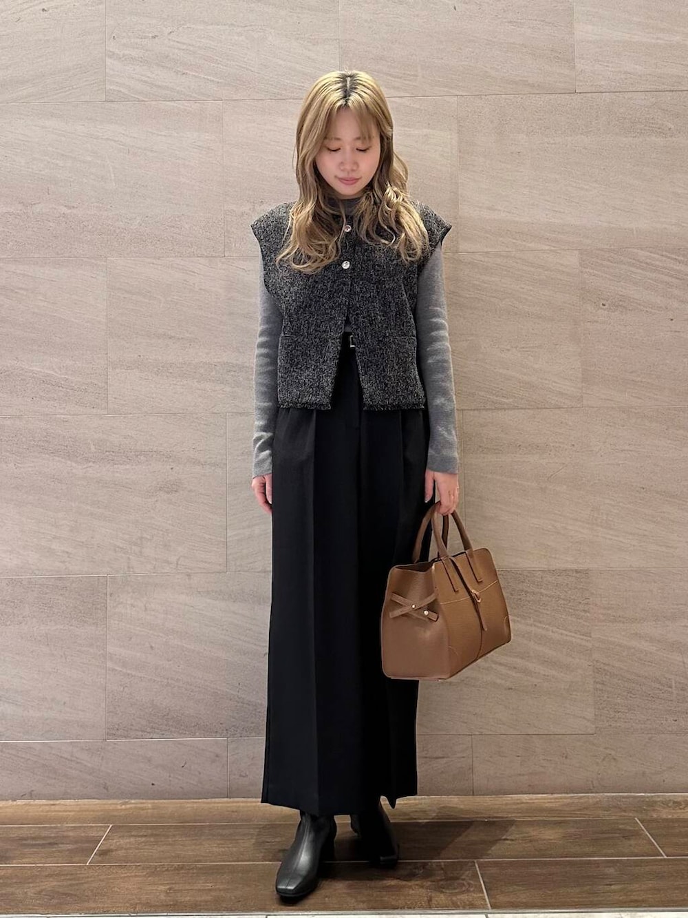 ブラウン系のハンドバッグ、グレー系のニット/セーター、ブラック系のその他パンツを着用したレディースの冬コーディネートの3枚目の写真