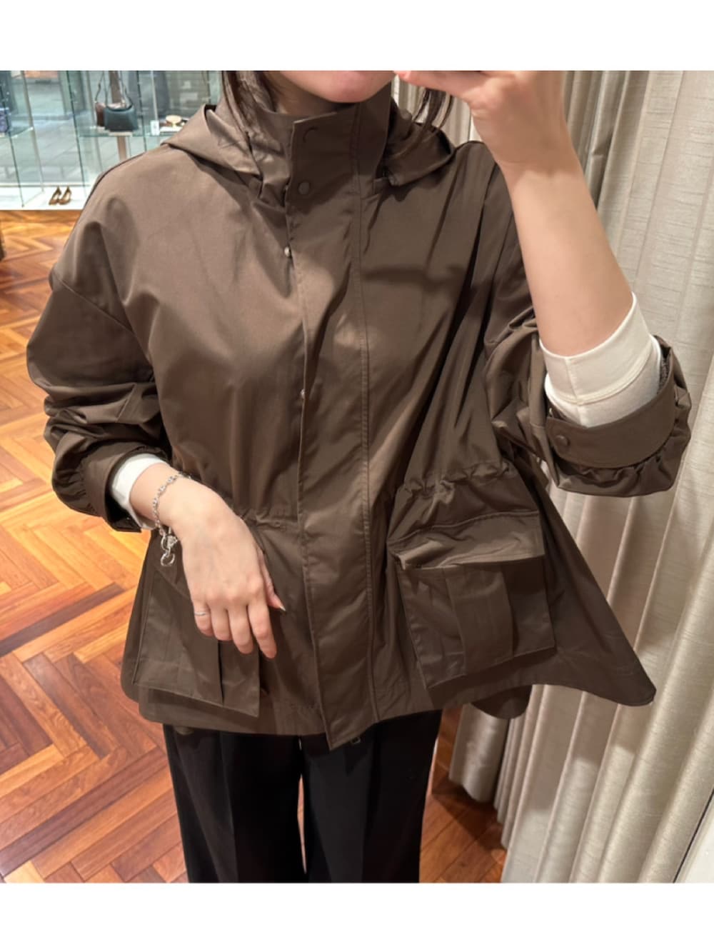 ブラウン系のマウンテンパーカー、ベージュ系のTシャツ/カットソー、シルバー系のブレスレットを着用したレディースの春コーディネートの2枚目の写真