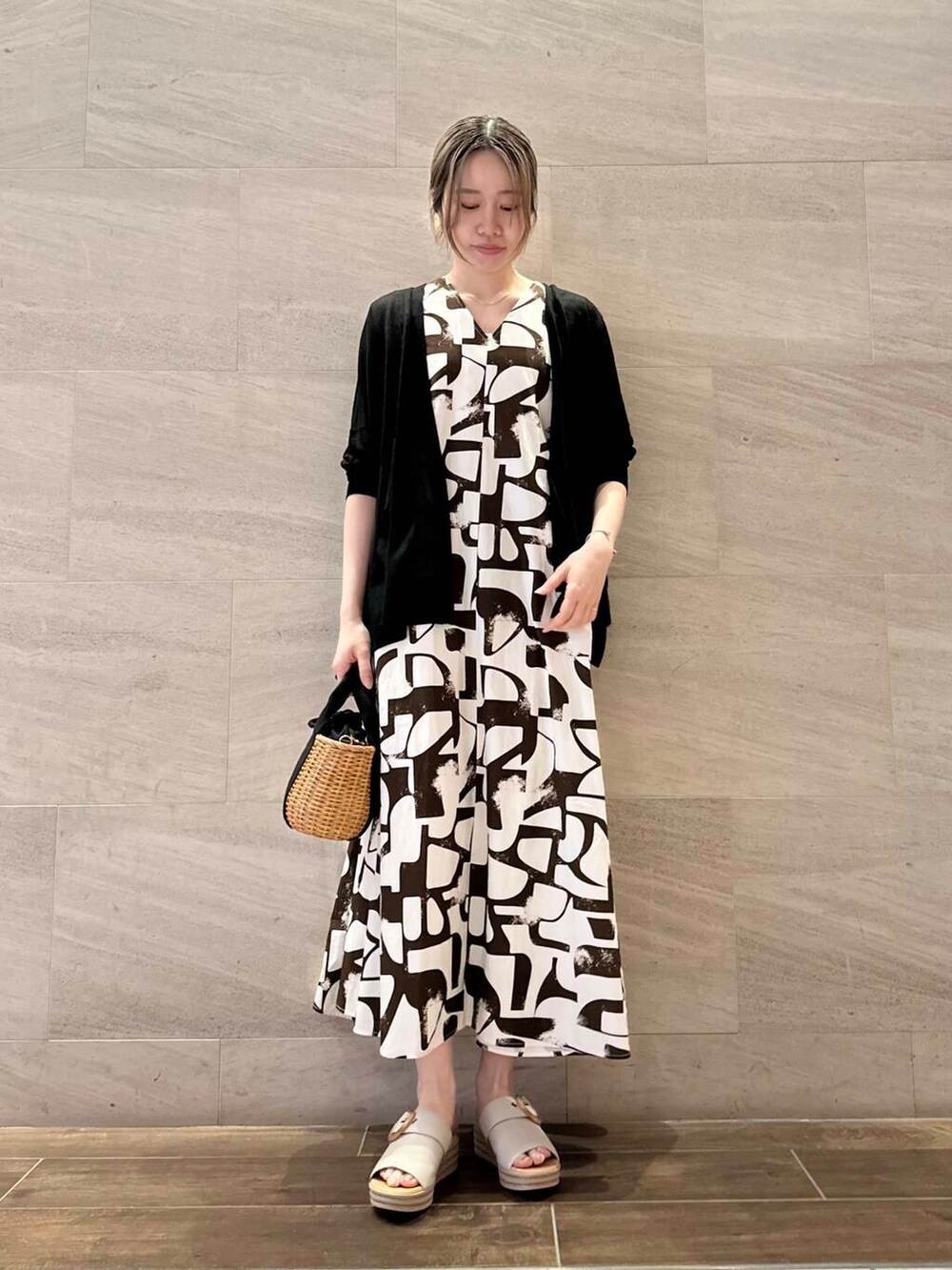 ブラック系のハンドバッグ、ブラック系のカーディガン/ボレロ、ブラウン系のワンピースを着用したレディースの春コーディネートの2枚目の写真