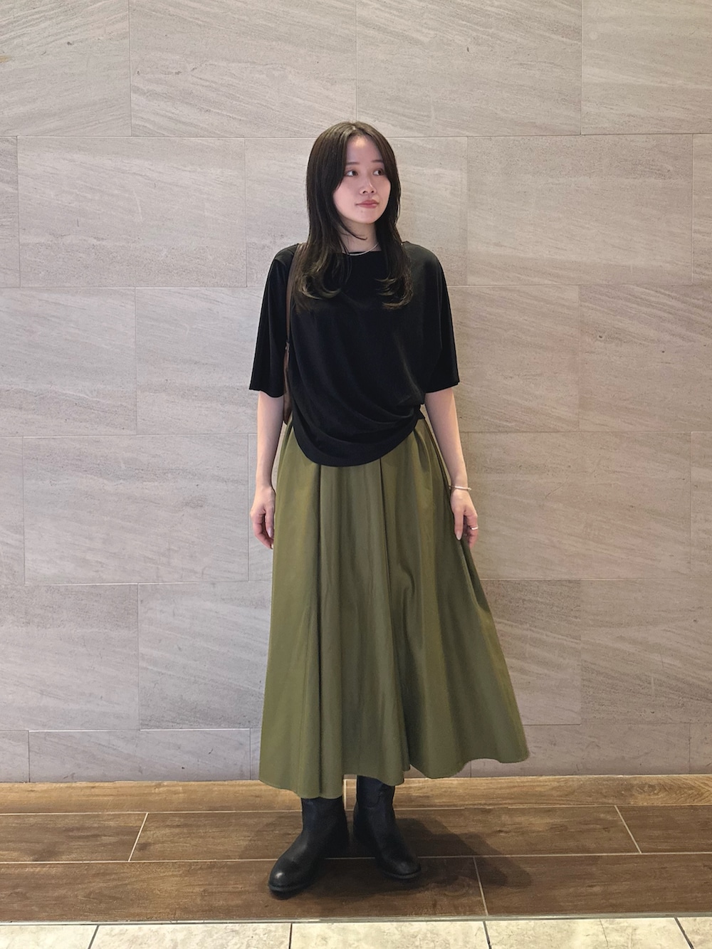 ブラック系のTシャツ/カットソー、グリーン系のスカート、ブラック系のブーツを着用したレディースの秋コーディネートの3枚目の写真