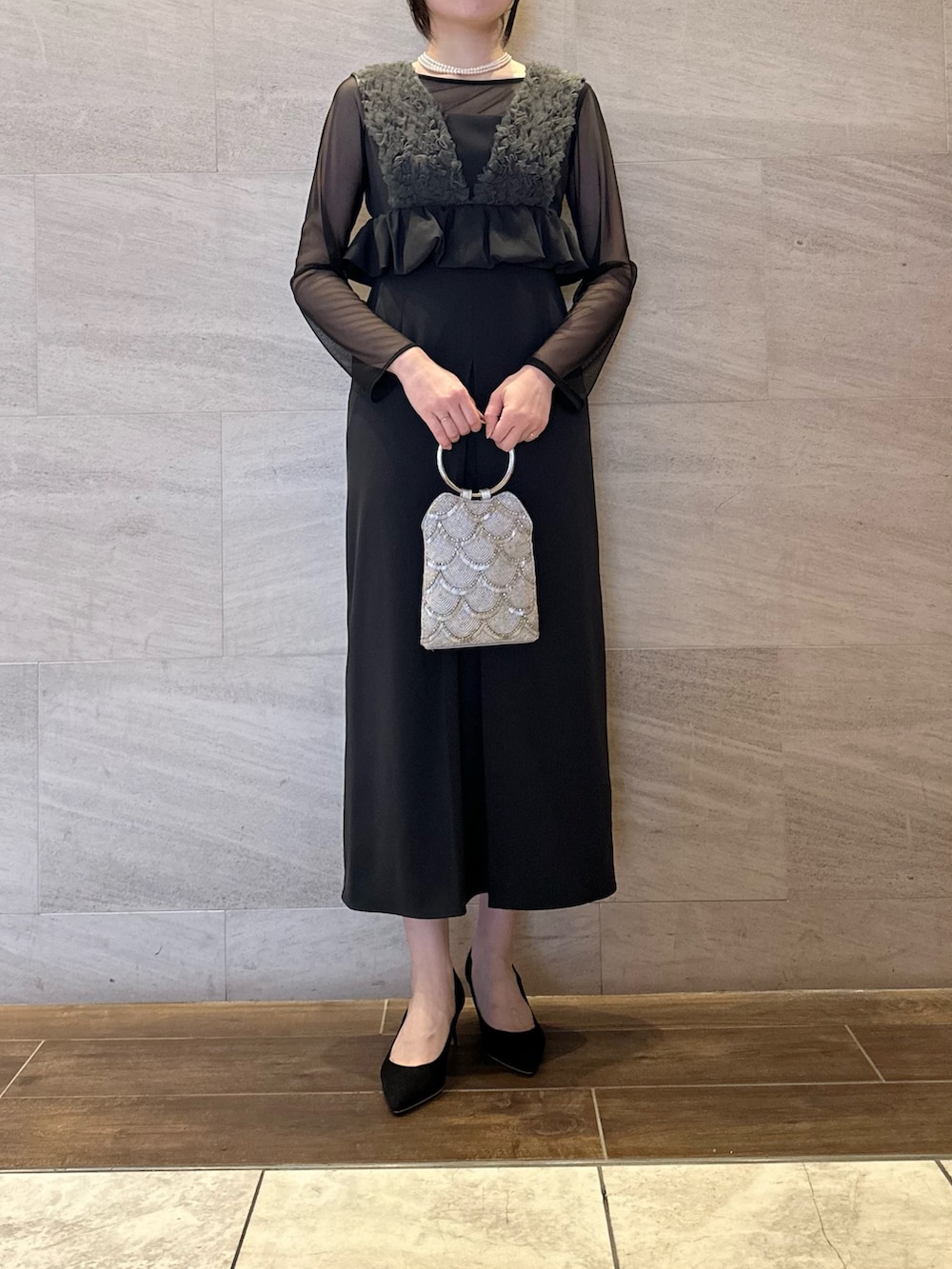グレー系のワンピース、シルバー系のハンドバッグ、ホワイト系のネックレスを着用したレディースの春コーディネートの4枚目の写真