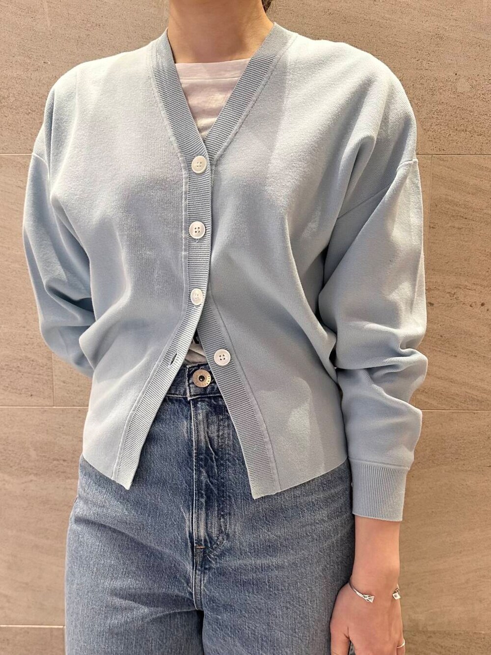 ブルー系のカーディガン/ボレロ、ブルー系のデニムパンツ、ブラウン系のショルダーバッグを着用したレディースの冬コーディネートの5枚目の写真