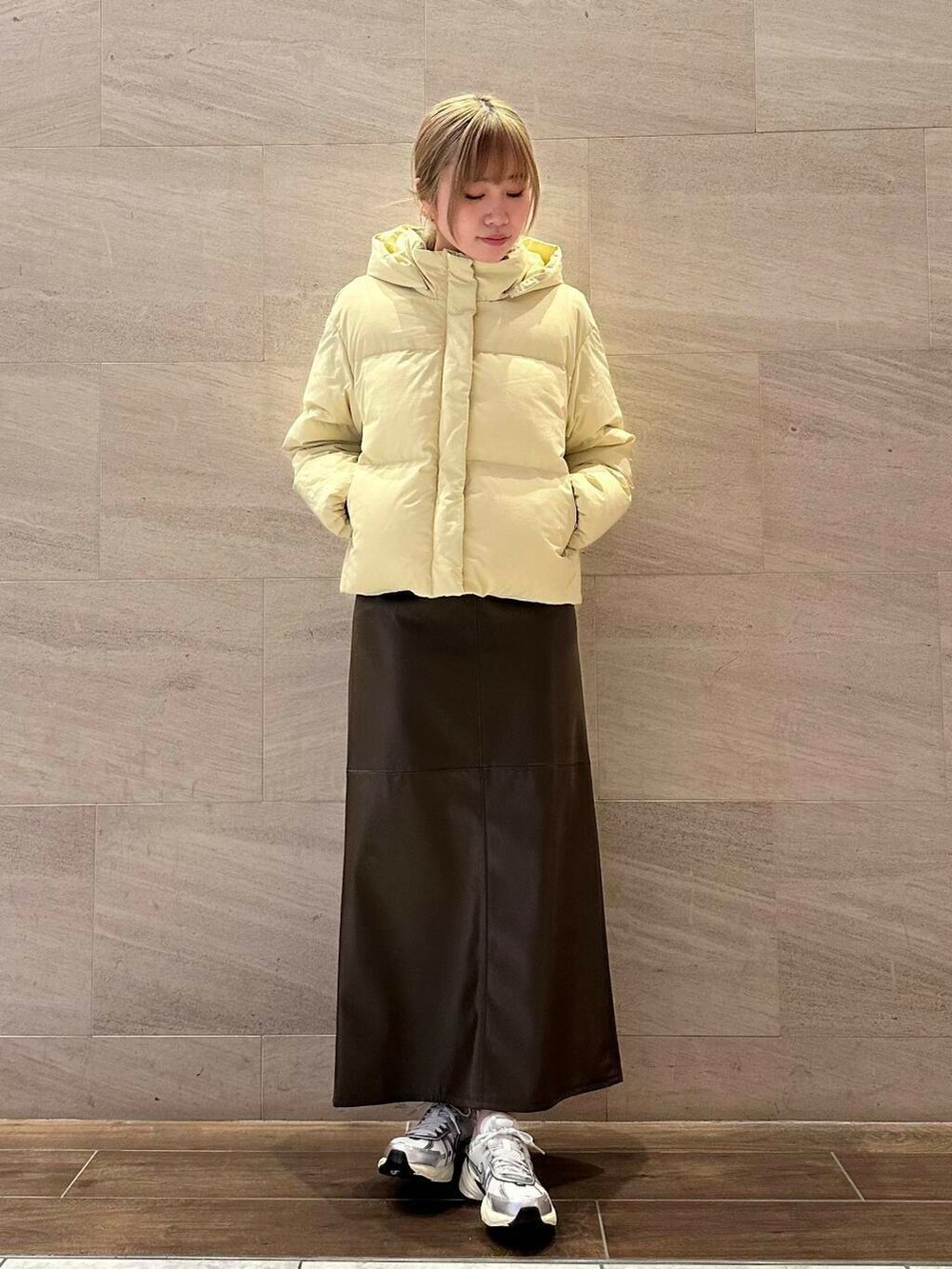 ブラウン系のスカート、イエロー系のダウンジャケット/コート、ホワイト系のスニーカーを着用したレディースの冬コーディネートの2枚目の写真
