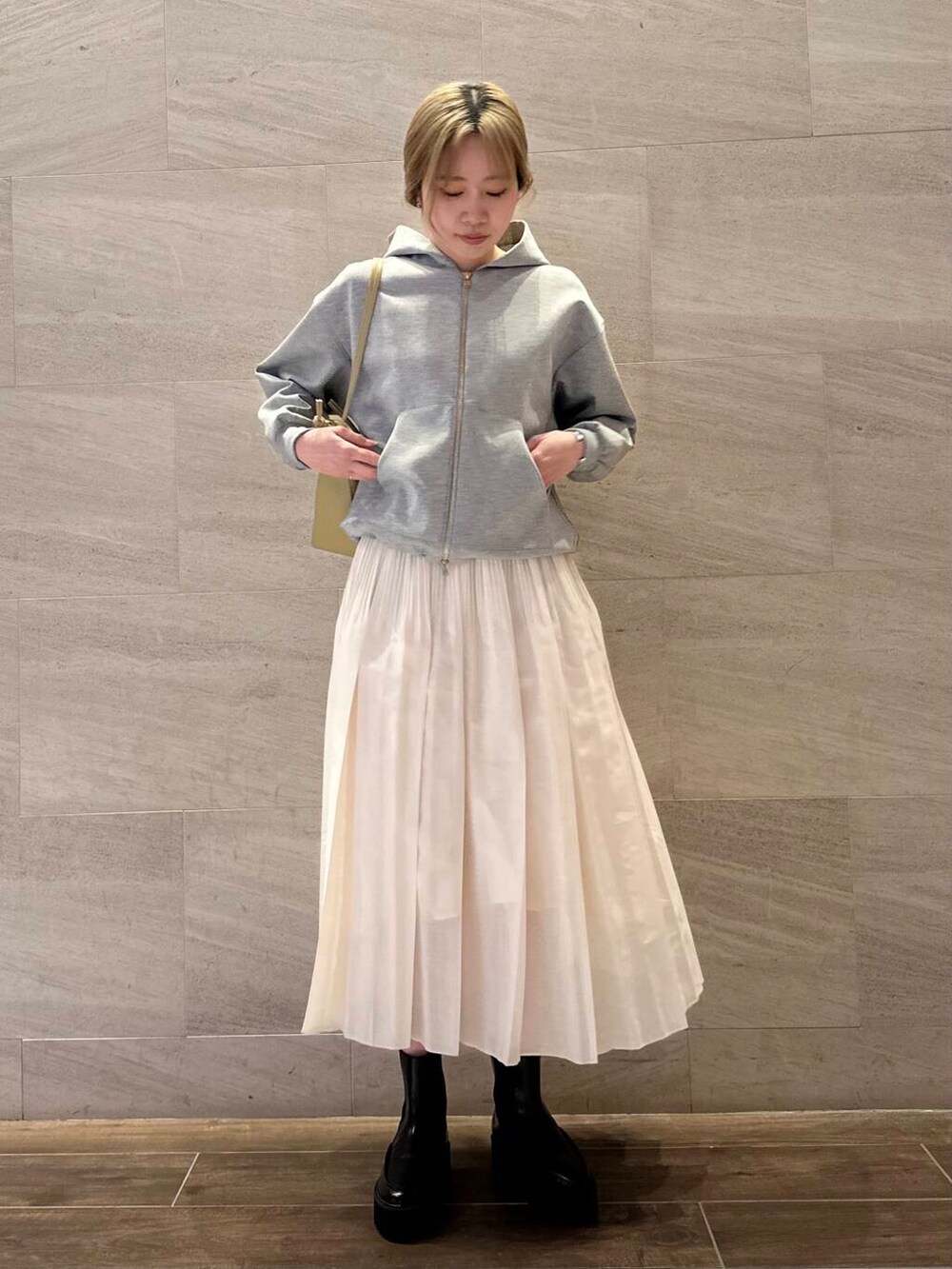 グレー系のブルゾン、ホワイト系のスカート、ベージュ系のショルダーバッグを着用したレディースの冬コーディネートの2枚目の写真