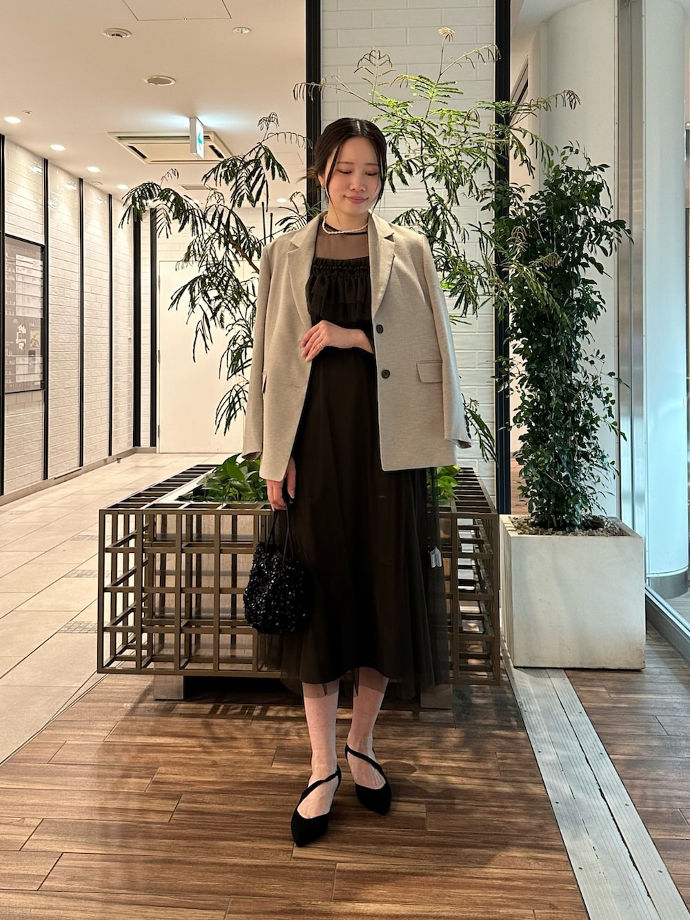 ベージュ系のその他アウター、ブラウン系のワンピース、ブラック系のハンドバッグを着用したレディースの春コーディネートの2枚目の写真