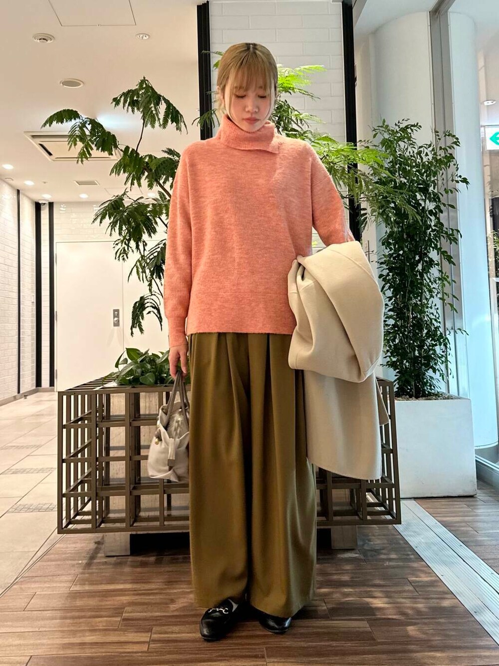 ベージュ系のステンカラーコート、ベージュ系のその他パンツ、ピンク系のニット/セーターを着用したレディースの冬コーディネートの3枚目の写真