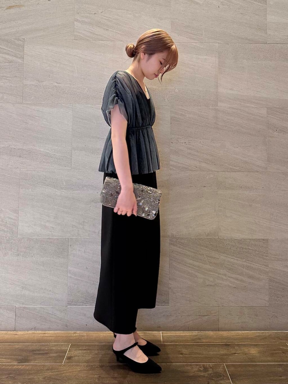 ゴールド系のハンドバッグ、ブラック系のパンプス、ブラック系のワンピースを着用したレディースの夏コーディネートの4枚目の写真