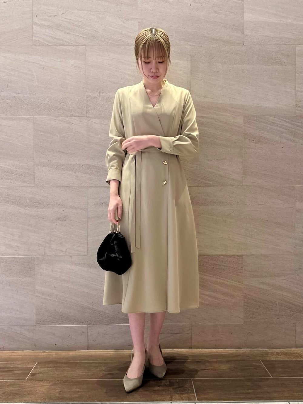 ブラウン系のパンプス、ブラック系のハンドバッグ、ベージュ系のワンピースを着用したレディースの冬コーディネートの3枚目の写真