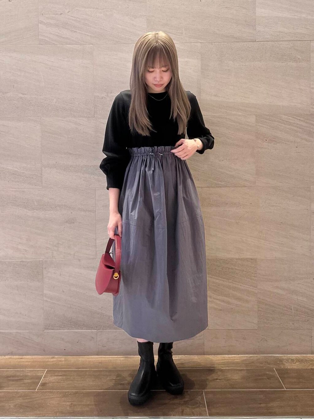 ブラック系のブーツ、ブラック系のワンピース、レッド系のハンドバッグを着用したレディースの冬コーディネートの3枚目の写真