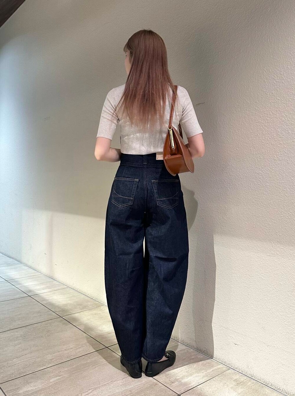 ブラック系のローファー、ホワイト系のニット/セーター、ブルー系のデニムパンツを着用したレディースの秋コーディネートの3枚目の写真