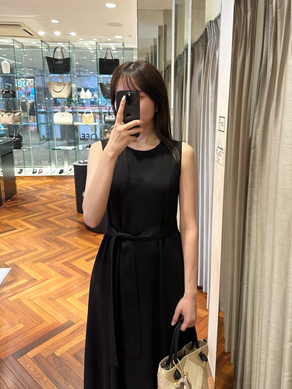ブラック系のワンピース、ベージュ系のショルダーバッグ、ブラック系のサンダルを着用したレディースの夏コーディネートの3枚目の写真