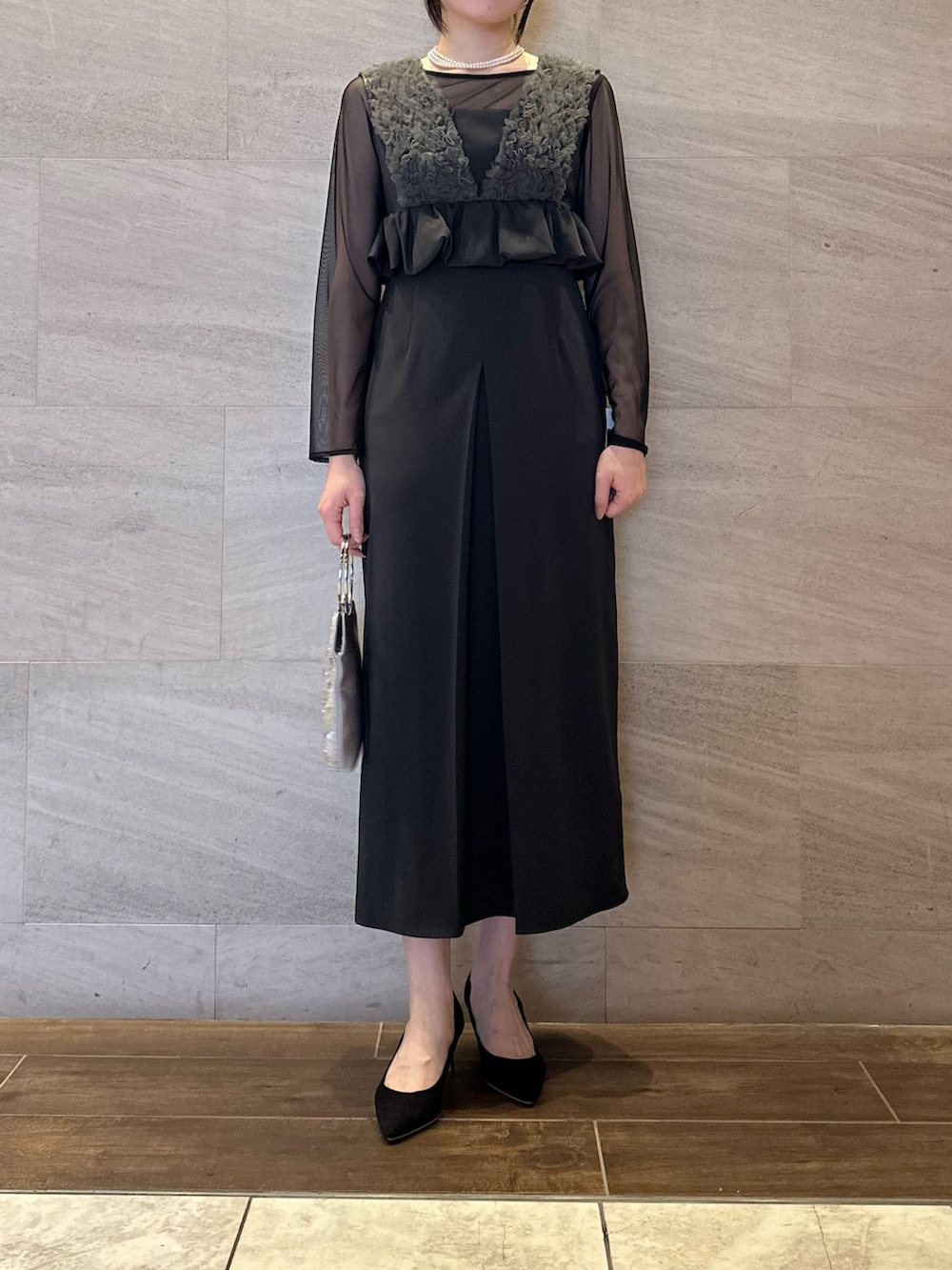 グレー系のワンピース、シルバー系のハンドバッグ、ホワイト系のネックレスを着用したレディースの春コーディネートの3枚目の写真