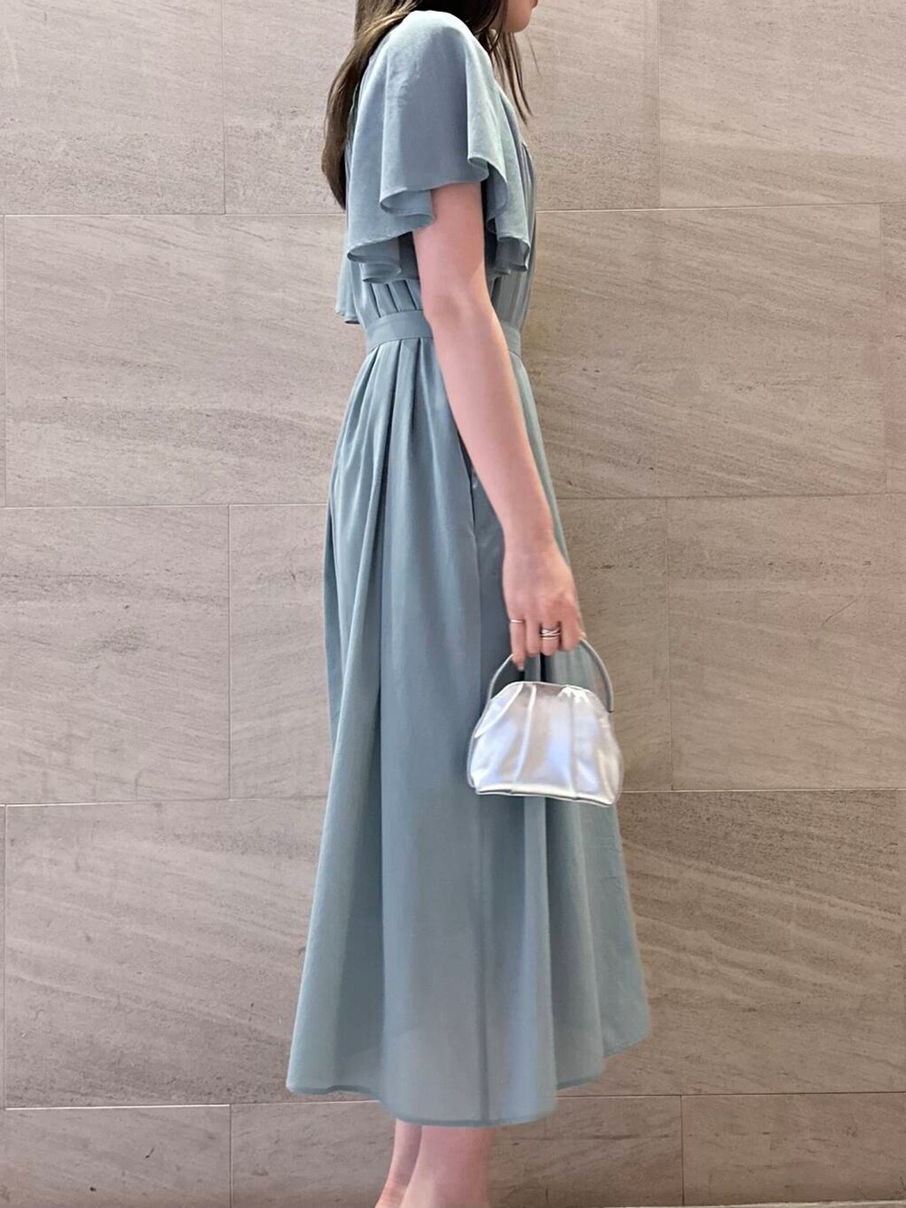 シルバー系のハンドバッグ、ブルー系のワンピース、シルバー系のリングを着用したレディースの夏コーディネートの3枚目の写真