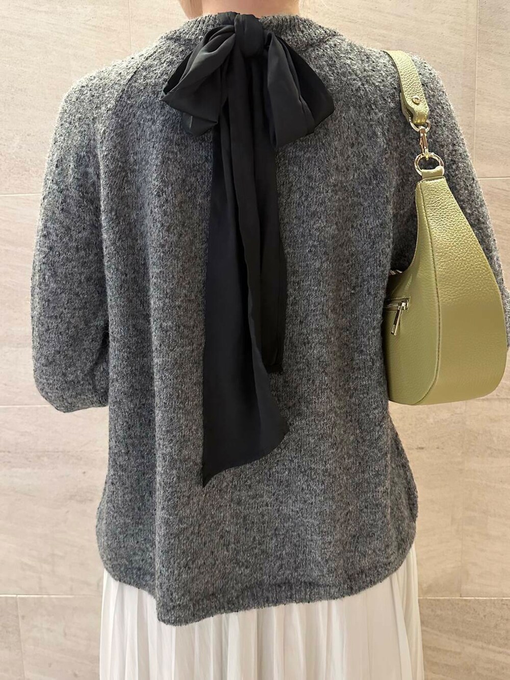 グリーン系のショルダーバッグ、ホワイト系のスカート、グレー系のニット/セーターを着用したレディースの冬コーディネートの6枚目の写真