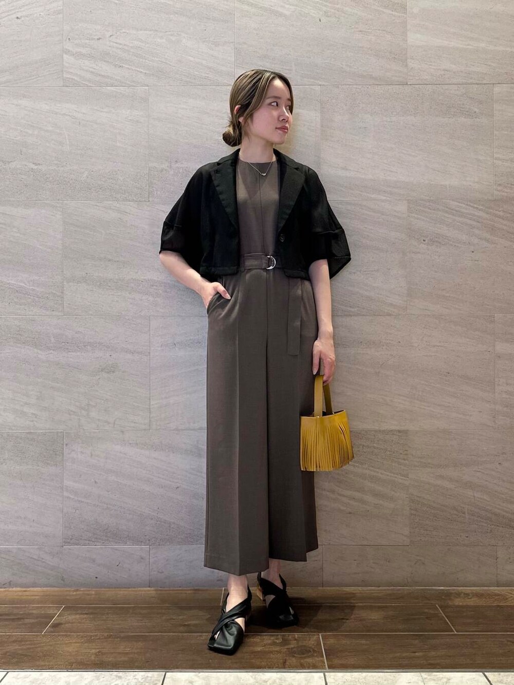 イエロー系のハンドバッグ、ブラック系のその他アウター、ブラウン系のサロペット/オーバーオールを着用したレディースの春コーディネートの4枚目の写真