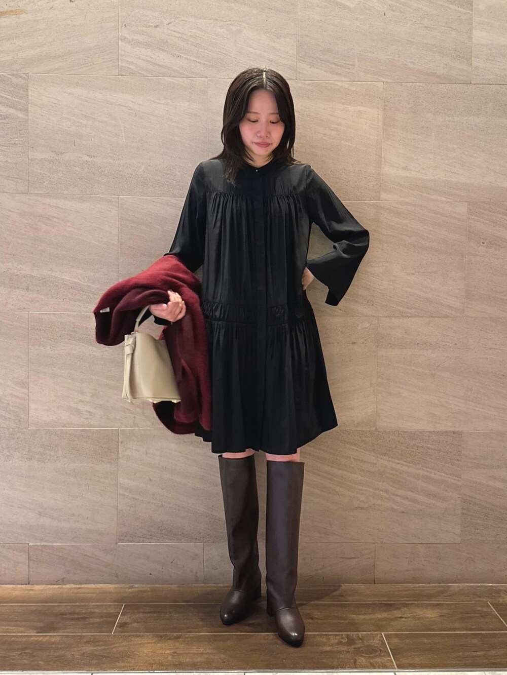 ブラック系のワンピース、レッド系のカーディガン/ボレロ、ベージュ系のハンドバッグを着用したレディースの秋コーディネートの4枚目の写真