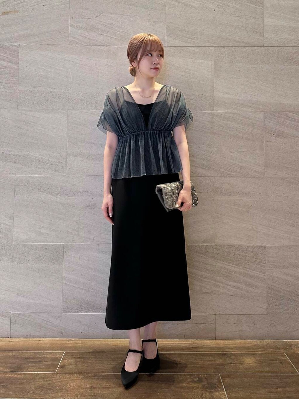 ゴールド系のハンドバッグ、ブラック系のパンプス、ブラック系のワンピースを着用したレディースの夏コーディネートの2枚目の写真